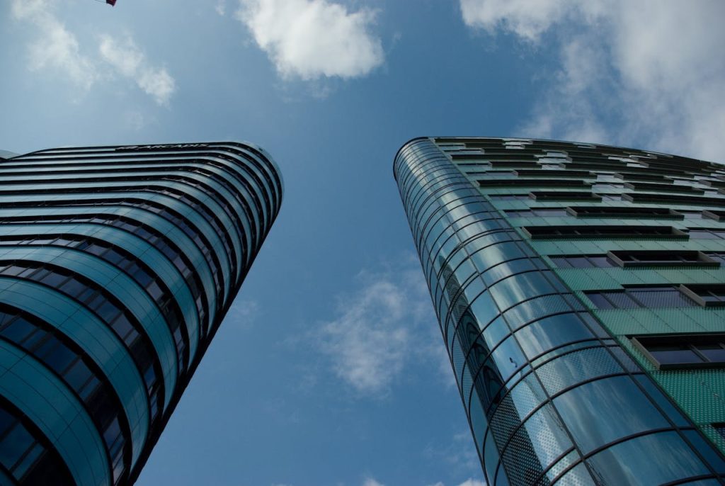 Low angle view of modern glass skyscrapers in an urban setting under a clear blue sky.
